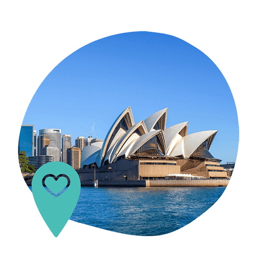 Sydney Opera House with its iconic white sails is set against a clear blue sky. A foreground heart-shaped location pin adds a touch of affection.